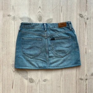 Lågmidjad jeanskjol från Lee - Ljusblå lågmidjad jeanskjol från Lee som jag har sytt upp från en längre kjol. Fint skick. Kan inte hitta storlek men skulle säga S. Tvärs över midjan är det ca 36 cm och längs med sidan är det 33 cm. Använd gärna köp nu!