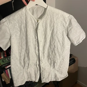 Vit kortarmad blus - Säljer en vit kortarmad blus med blommigt mönster. Köpt på en vintage butik, men är fortfarande i bra skick.