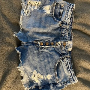 lågmidjade shorts - detta är ett par jättesnygga lågmidjade shorts med hål och fransar på kanterna. de har fem fickor och fem knappar. de är även i jättebra skick. inga fläckar eller hål. de är i storlek 40 men passar mig bra med 38