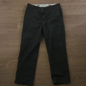Mörk gråa byxor från Dickies - Säljer ett par klassiska svarta byxor från Dickies, modell 874. Byxorna har en rak passform och är tillverkade i slitstarkt material. Perfekta för en stilren look.