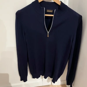 Mörkblå merinoull half zip från Stenströms - Snygg mörkblå tröja från Stenströms i 100% merinoull. Tröjan har en dragkedja framtill och ribbade detaljer vid kragen. Perfekt för kyligare dagar.