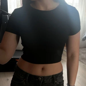 Svart ribbad topp från Even&Odd - Snygg svart ribbad topp från Even&Odd. Denna kortärmade topp har en croppad passform som ger en trendig look. Perfekt för att matcha med höga jeans eller kjolar.