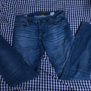 Blå jeans från Jack & Jones - Snygga blå jeans från Jack & Jones med klassisk femficksdesign och dragkedja. Perfekta för en avslappnad stil. Märkeslapp i brunt läder baktill.