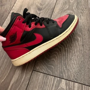 Nike Air Jordans i svart och rött - Snygga Nike Air Jordans i svart och rött med klassisk design. Skorna har snörning och en kontrasterande vit sula. Perfekta för en sportig look.