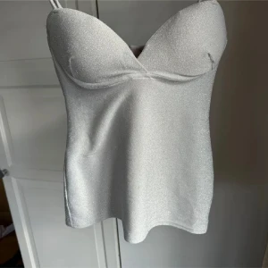 Glittrig silverfärgad korsettopp - Snygg och glittrig silverfärgad korsettopp med smala axelband. Perfekt för fest❣️
