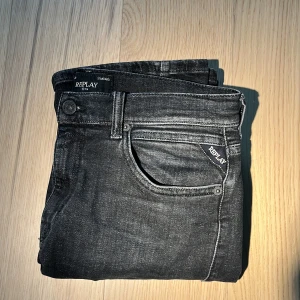Svarta jeans från Replay - Snygga svarta jeans från Replay med klassisk femficksdesign och knappgylf. Perfekta för en stilren look. Märkesdetaljer på fickan ger en extra touch. Knappt använda och säljer det riktigt billigt.