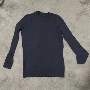 Mörkblå stickad tröja - Säljer en stilren mörkblå tröja med långa ärmar och ribbad nederkant. Perfekt för en avslappnad och snygg look. Passar bra till både jeans och chinos.