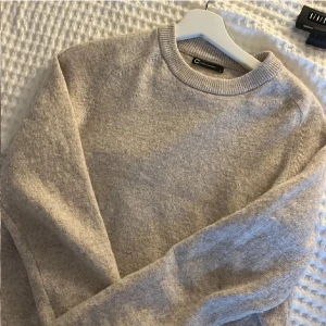 Beige tröja i bomull/ull-blandning - Fri frakt!! Passa på att handla! Nypris: 600kr. Säljer en stilren beige tröja från märket Cubus. tillverkad i en mjuk bomull/ull-blandning. Tröjan har en klassisk rund hals och långa ärmar, perfekt för kyligare dagar. Ett måste i garderoben för en avslappnad och bekväm stil. Storlek S. 
