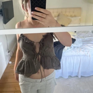 Brun volangtopp med knytning - Säljer en brun topp med volangdetaljer och knytning framtill. 
