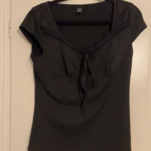 Svart kortärmad topp med spets  - Snygg svart topp från Shein med korta ärmar och knytning framtill. Perfekt för en stilren look. Tillverkad i ett mjukt och bekvämt material.