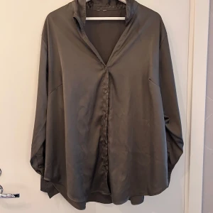Blus  - Satinblus med knappar framtill och vid ärmarna 