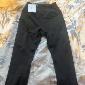 Svarta leggings med fickor från Gymshark - Snygga svarta leggings från Gymshark i body fit med praktiska fickor. Perfekta för träning eller en aktiv dag. Säljer dessa för dem inte passar mig och är helt oanvända