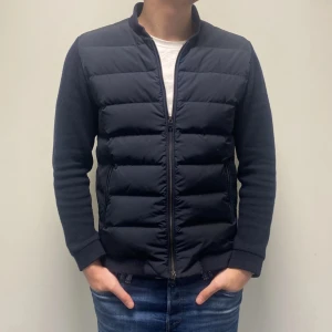 Cardigan från Woolrich - Säljer en stilren mörkblå cardigan från Woolrich. Jackan har en dragkedja framtill och långa ärmar. Perfekt året runt med sin quiltade design som håller värmen bra. Storlek L men sitter som M och i extremt bra skick! Nypris 5000+