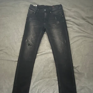 Svarta jeans från Vingino - Snygga svarta jeans från Vingino med slitna detaljer och en tight passform. Perfekta för en trendig look. Jeansen har klassisk femficksdesign och knappgylf.