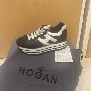 Svart och vit sneaker från Hogan - Snygga svarta och vita sneakers från Hogan med en hög sula och klassisk snörning. Perfekta för en stilren look med en modern touch.