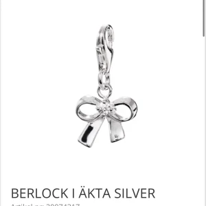 Berlock i äkta silver med rosett - Pris kan diskuteras. Fick den i födelsedags present och hade redan en sen i julas,därav säljer jag den nya. Elegant berlock i äkta silver från MOOD Charms, formad som en rosett med en gnistrande kubisk zirkonia i mitten. Perfekt för att ge ditt armband en personlig touch. Berlocken är 10,8 mm bred och 20,5 mm hög.
