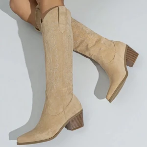 Beige cowboy boots i mocka - Snygga beige cowboy boots i mocka med broderade detaljer och en låg klack.