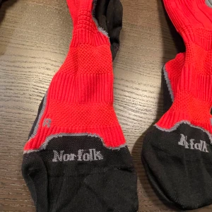 Röda och svarta kompressionsstrumpor från Norfolk - Säljer två  par röda och svarta strumpor från Norfolk. Perfekta för sport eller vardagligt bruk.