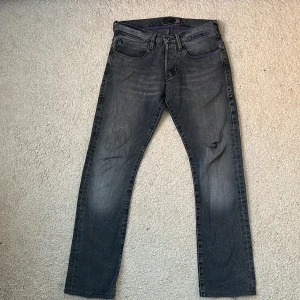 Grå jeans med raka ben från Lee - Snygga grå jeans med raka ben och klassisk femficksdesign. De har en knappgylf och bälteshällor, vilket gör dem perfekta för en avslappnad stil. Detaljer i lila på insidan av linningen ger en unik touch. Sitter som W30 L32