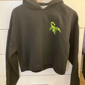 Cropped hoodie med tryck - Inköpt på New Yorker 2022, använd ett par gånger sen dess. Har ett justerbart snöre vid midjan som man kan dra åt eller göra lösare beroende vilken passform man vill ha. Trycket har hållt bra i tvätten. Den har inga snören på luvan som andra hoodies. Har XL i vanliga fall och den sitter ok på mig! 