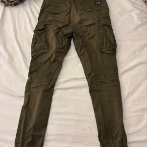 Olivgröna cargobyxor - Snygga olivgröna cargobyxor med flera praktiska fickor på sidorna. Perfekta för en avslappnad och funktionell stil. Byxorna har en normal passform och är tillverkade i ett slitstarkt material.