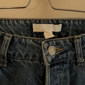 Blå jeans från H&M - Snygga blå jeans från H&M med klassisk femficksdesign och knappgylf. Perfekta för en avslappnad stil. Bootcut/straight leg