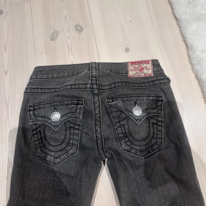 Mörkgråa jeans från True Religion - Snygga mörkgråa jeans från True Religion med bakfickor och silverfärgade knappar. De är i storlek 25 och modellen är straight🥰 