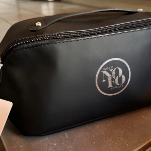 Svart necessär från NOFO! - Snygg svart necessär i smart design med många fack och handtag. Mått: 20 x 10 cm. Ny!