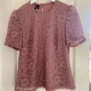 Rosa spetsblus från Pieces - Säljer en söt rosa spetsblus med korta ärmar och rund hals. knäppning i nacken. Från Pieces. Har använt den 2 gånger ungefär.