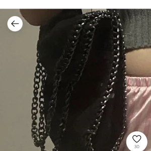 Svart axelväska med kedjedetaljer - Snygg svart axelväska med coola kedjedetaljer. Perfekt för att ge din outfit en edgy touch. Väskan har en stilren design och passar till många olika stilar.