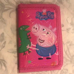Peppa Pig Barn plånbok - Söt rosa plånbok med Peppa Pig-motiv. Plånboken har en färgglad design med Peppa Pig och dinosaurie på framsidan. Perfekt för barn som älskar Peppa Pig! Helt ny, 55kr/st , sammafrakt 