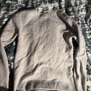 John Henric tröja - Säljer en stilren grå tröja från John Henric. Tröjan har en klassisk design med rund hals och ribbstickade muddar vid ärmslut och nederkant. Perfekt för en elegant och avslappnad look. Den har krympt i tvätten så sitter ungefär som en s. Tröjan är i kashmirmix och har ett nypris på 1500kr. 