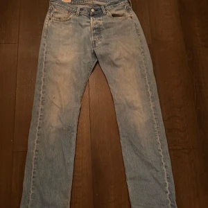 Levis 501 jeans i ljusblå denim - Klassiska Levis 501 jeans i ljusblå denim. Dessa jeans har en rak passform och knappar i gylfen. Perfekta för en avslappnad stil. W30 L32