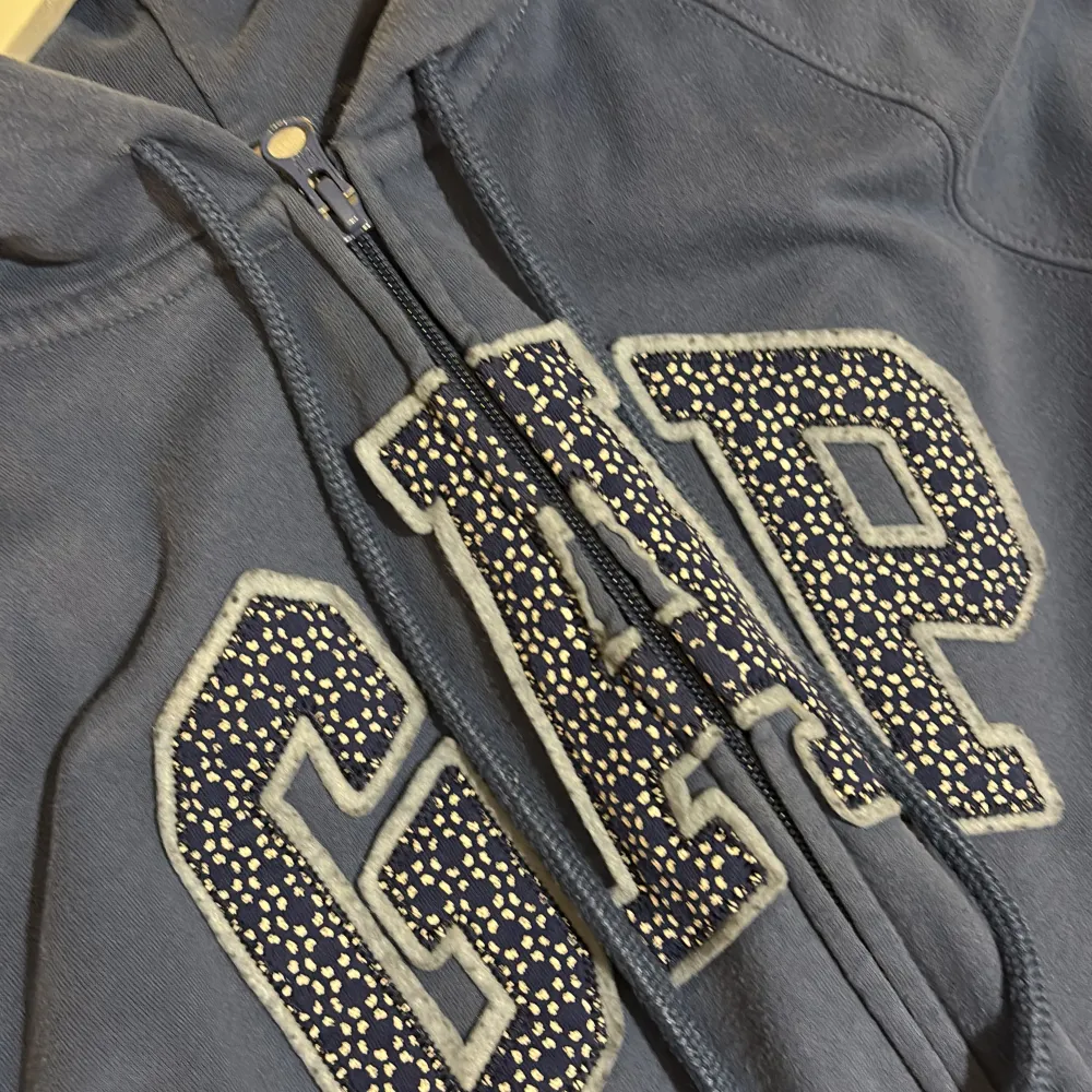 Säljer en blå hoodie från GAP med dragkedja och stor logga framtill. Tröjan har en bekväm passform med långa ärmar och en praktisk huva. Mysig inuti. Använt några gånger men är ”gått som ny” ändå. Stl S. Neuletakit & Villapaidat.