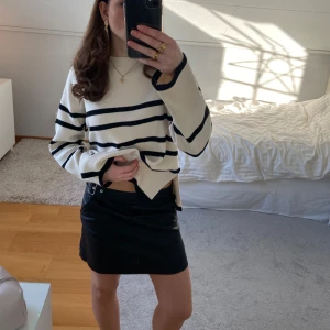 Svart skinn kjol med bälte - Snygg svart kjol i skinnimitation med ett silver bälte och fickor. Perfekt för en trendig look. Sliten (se sista bilden)🩷