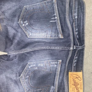 Mörkblå lågmidjade True Religion jeans - Snygga mörkgrå lågmidjade jeans från True Religion med slitna detaljer och klassisk femficksdesign. .