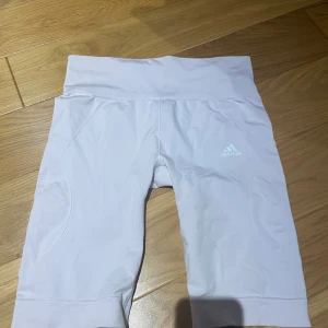 Ljusrosa träningsshorts från Adidas - Snygga vita träningsshorts från Adidas med hög midja och logotyp på sidan. Perfekta för träning och aktiva dagar. Tillverkade i ett bekvämt och stretchigt material.