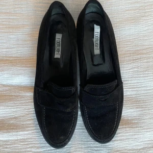 Svarta loafers från Footlight - Snygga svarta loafers från Footlight i mocka. Skorna har en klassisk design med en låg klack och en robust sula för extra komfort. 