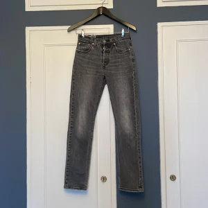 Grå Levis 501 jeans - Säljer ett par klassiska grå Levis 501 jeans. De har en rak passform och är högmidjade med den ikoniska Levis-lappen baktill. Perfekta för en avslappnad stil.