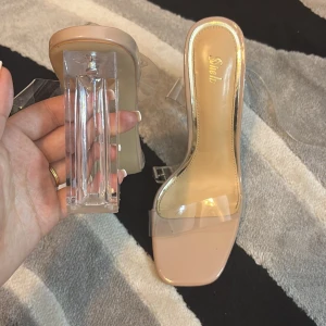 Beige klackskor med transparent rem - Snygga beige klackskor från Shein med transparenta remmar och en fyrkantig tå. Skorna har en unik genomskinlig klack som ger en modern touch. Perfekta för att lyfta din stil till nästa nivå.