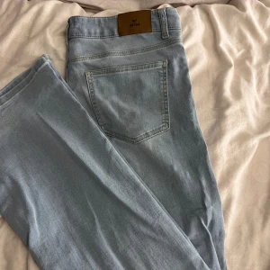 Ljusblå lågmidjade jeans från Nelly - Snygga ljusblå jeans från Nelly med klassisk femficksdesign och knappgylf. Perfekta för en avslappnad stil. Lite slitna vid längst ned vid fötterna därav priset. Säljer då dem ej används längre! 