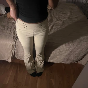 Beige byxor med knappar - Snygga beige byxor med dekorativa knappar vid midjan. Byxorna har en bootcut-stil som ger en trendig look. Passar strl xs-m beroende på hur man vill att den sitter, Skriv för fler bilder🩷