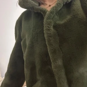 Grön teddyjacka från Only - Mysig grön teddyjacka från Only med långa ärmar. Perfekt för kyliga dagar när du vill hålla dig varm och stilren. Jackan har en mjuk och fluffig yta som ger en skön känsla.