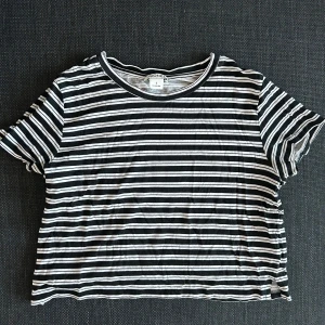 Svartvit randig t-shirt från Monki - Säljer en svartvit randig t-shirt från Monki. Den har korta ärmar och en rund halsringning. Perfekt för en avslappnad stil.