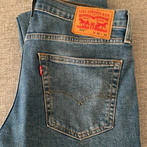 Levi's 513 jeans - Snygga blå Levi's 513 jeans med klassisk femficksdesign och dragkedja. De har en straight passform och är tillverkade i ett hållbart denimtyg. Perfekta för en avslappnad stil.