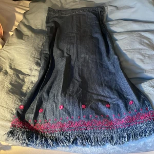 Jeanskjol - Snygg kjol i tunt jeanstyg från Duster. Söta broderier längst ner och dragkedja i sidan. Midjemått: 36 cm, längd: 85 cm
