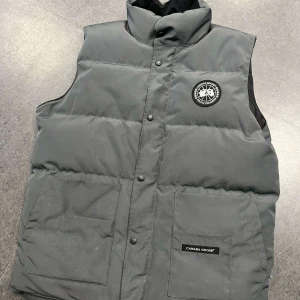 Canada goose väst black label - Skön grå canada goose väst med black label. Riktig snygg nu till vintern och hösten och är i bra skick. Är en XL MEN SITTER MED SOM EN L/M. Vid fler frågor och funderingar är det bara att höra av sig. Priset är ej hugget i sten! 