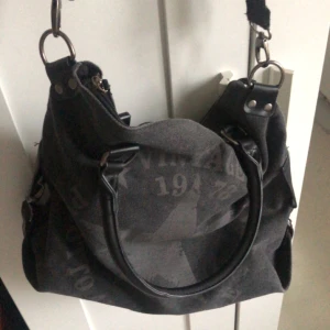 Axelremsväska - Säljer en svart axelremsväska med snyggt tryck på framsidan, justerbara remmar. Minns inte vart jag köpte den ifrån, så det är oklart. Det ryms väldigt mycket i den så perfekt att ha som skolväska t.ex. ! 👜