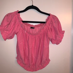 Rosa blus från Gina Tricot - Säljer en superfin rosa blus från Gina Tricot. Den har korta puffärmar och ett sött mönster med små hål. Blusen är elastisk vid halsen och midjan, vilket ger en bekväm passform. Använd ett fåtal gånger så i väldigt fint skick 