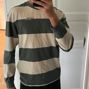 Randig långärmad tröja - Säljer en randig tröja från H&M i storlek S. Den har breda ränder i grönt och beige och är perfekt för en avslappnad stil. Tröjan är långärmad och har en relaxed fit. Perfekt för höst och vår! Plagget är knappt använt.